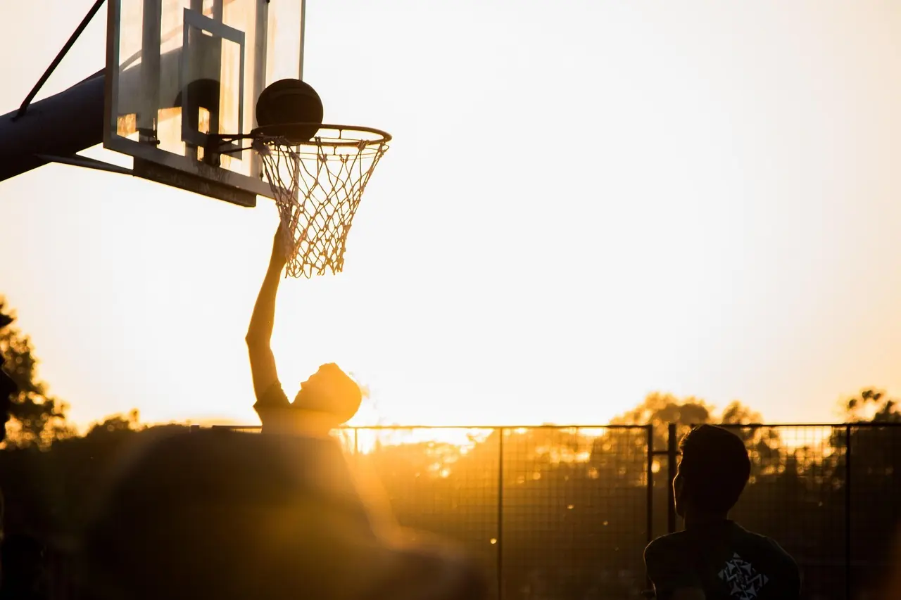 Basketballspiller laver layup i solnedgang